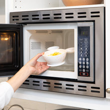 Load image into Gallery viewer, A hand places a Bumkins Silicone First Feeding Set: Mickey Mouse Vanilla Sprinkle filled with food into an open microwave.
