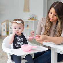Load image into Gallery viewer, A woman feeds a baby in a high chair with a Bumkins Silicone Dipping Spoons: Minnie Mouse (Black and Pink) from a pink bowl on the tray.
