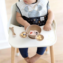 Load image into Gallery viewer, A baby sits in a high chair, a Bumkins Silicone First Feeding Set: Minnie Mouse Gold with yogurt, berries, and snacks on the tray.
