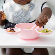 Load image into Gallery viewer, A baby sits in a high chair, enjoying mealtime with the Bumkins Silicone First Feeding Set: Minnie Mouse Light Pink.
