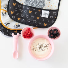 Load image into Gallery viewer, Bumkins Silicone First Feeding Set: Minnie Mouse Light Pink is filled with yogurt and berries, sitting next to bibs on a white background.

