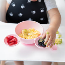 Load image into Gallery viewer, A child in a high chair enjoys scrambled eggs from a Bumkins Silicone First Feeding Set: Minnie Mouse Light Pink, with berries on the side.
