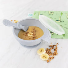 Load image into Gallery viewer, Bumkins Silicone First Feeding Set: Gray with banana puree sits among banana slices and granola and a llama print pouch on a marble surface.
