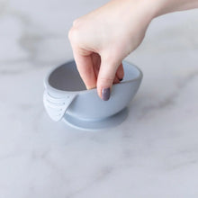 Load image into Gallery viewer, A hand holds a Bumkins Silicone First Feeding Set: Gray, demonstrating the suction cup bottom on a marble surface.
