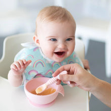 Load image into Gallery viewer, A smiling baby sits in a high chair as an adult feeds them from a pink bowl with a pink Bumkins Silicone Dipping Spoons 3 Pack: Lollipop.
