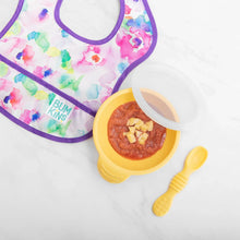 Load image into Gallery viewer, Bumkins Silicone First Feeding Set: Pineapple filled with mashed food sits next to a colorful floral bib on a marble background.

