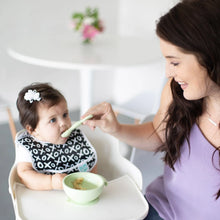 Load image into Gallery viewer, A woman smiles as she feeds a baby in a high chair from a green bowl with a Bumkins Silicone Dipping Spoons 3 Pack: Taffy.

