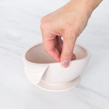 Load image into Gallery viewer, A hand holds a Bumkins Silicone First Feeding Set: Sand, demonstrating the suction cup bottom on a marble surface.
