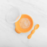 Bumkins Silicone First Feeding Set: Tangerine holds pureed food on a marble background.