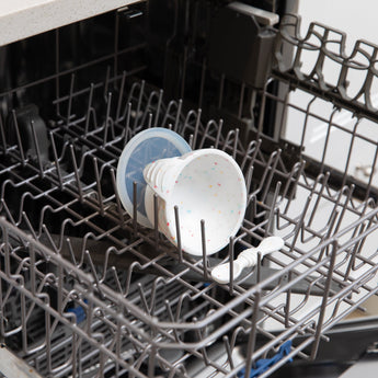 Bumkins Silicone First Feeding Set: Vanilla Sprinkle sits in the top rack of an open dishwasher.