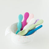 Bumkins Silicone First Feeding Set: Vanilla Sprinkle with colorful baby spoons inside on a white background.