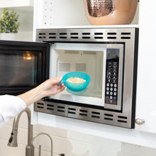 Load image into Gallery viewer, A person places a Bumkins Silicone First Feeding Set: Blue Jelly with oatmeal into an open microwave.
