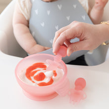 Load image into Gallery viewer, Close-up of an adult hand using a Bumkins Silicone Chewtensils®: Pink Jelly to scoop yogurt from a pink bowl in front of a baby.
