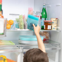 Load image into Gallery viewer, A child reaching into an open fridge to grab a Bumkins Silicone Flat Reusable Bag 2 Pack, Blue among other bags, food, and drinks.
