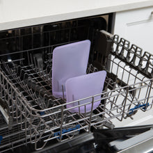 Load image into Gallery viewer, Bumkins Silicone Flat Reusable Bag 2 Pack, Lavender sits in the top rack of an open dishwasher.
