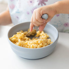 Load image into Gallery viewer, Close-up of a child enjoying mac and cheese from Bumkins Silicone Grip Bowl: Gray using a spoon at a white table.
