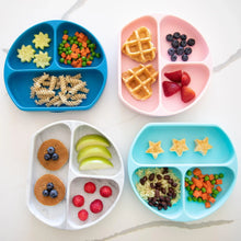 Load image into Gallery viewer, Bumkins Silicone Grip Dish: Blue is arranged among other similar dishes on a white marble surface, all holding toddler meals.
