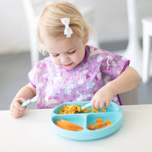 Load image into Gallery viewer, A toddler in a purple bib enjoys macaroni and veggies from a Bumkins Silicone Grip Dish: Blue with a fork at a white table.
