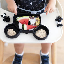 Load image into Gallery viewer, Close-up of a child in a high chair enjoying watermelon &amp; cereal from a divided plate with Bumkins Silicone Chewtensils®: Mickey Mouse nearby. 
