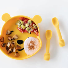 Load image into Gallery viewer, Bumkins Silicone Grip Dish: Winnie The Pooh holds fruit, toast, and yogurt near two yellow baby spoons on a white background.
