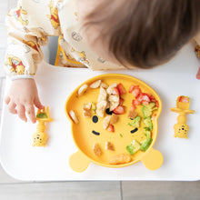Load image into Gallery viewer, A child enjoys fruit and avocado from a Bumkins Silicone Grip Dish: Winnie The Pooh with matching utensils, seated in a high chair.

