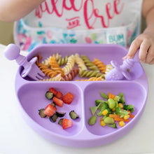 Load image into Gallery viewer, Close-up of a child enjoying food from a Bumkins Silicone Grip Dish: Lavender with matching utensils while wearing a colorful bib.
