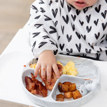 Load image into Gallery viewer, Close-up of a child in a black &amp; white bib reaching for breakfast foods from a Bumkins Silicone Grip Dish: Marble on a high chair tray.
