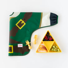 Load image into Gallery viewer, Bumkins Silicone Grip Dish: Zelda™ Triforce with fruit and avocado sits next to a folded bib and yellow baby utensils on a white background.

