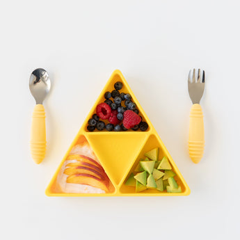 Bumkins Silicone Grip Dish: Zelda™ Triforce holds berries, peaches, and avocado next to yellow handle utensils on a white background.