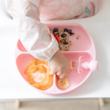 Load image into Gallery viewer, Close-up of a toddler reaching for food from a Bumkins Silicone Grip Dish: Pink on a high chair tray.
