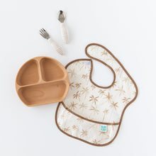 Load image into Gallery viewer, Bumkins Silicone Grip Dish: Wood Grain sits on a white background next to beige utensils and a beige &amp; brown bib on a white background.
