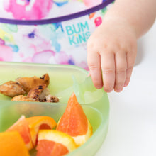 Load image into Gallery viewer, Close-up of a toddler reaching for food from a Bumkins Silicone Grip Dish: Green Jelly, with a colorful bib in the background.
