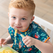 Load image into Gallery viewer, A young child with short red hair smiles while holding a fork with pasta, eating from Bumkins Silicone Grip Dish: Green Jelly.
