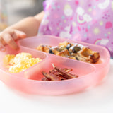 Close-up of a child eating eggs, bacon, & blueberry-topped waffles from a Bumkins Silicone Grip Dish: Pink Jelly.