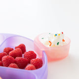 Close-up of Bumkins Silicone Grip Dish: Purple Jelly with raspberries and a pink cup of whipped cream on a white background.