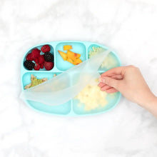 Load image into Gallery viewer, A hand lifts the lid of Bumkins Silicone Grip Dish with Lid (5 Section): Blue with fruit and mashed food on a marble surface.
