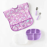 Bumkins Silicone Grip Dish with Lid (5 Section): Lavender, utensils, and a unicorn-patterned bib are neatly arranged on a white background.