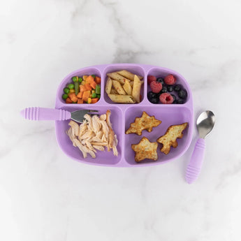 Bumkins Silicone Grip Dish with Lid (5 Section): Lavender with chicken, veggies, pasta, berries, potatoes, & utensils on a marble surface.