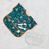 Bumkins Silicone Grip Dish with Lid (5 Section): Marble lies next to a blue & orange animal themed bib and utensils on a marble surface.