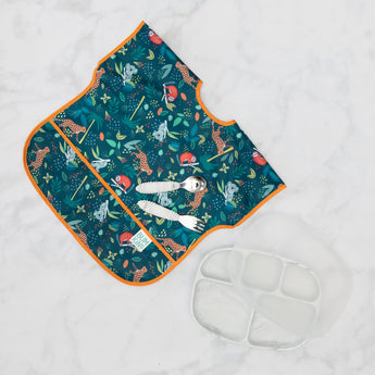 Bumkins Silicone Grip Dish with Lid (5 Section): Marble lies next to a blue & orange animal themed bib and utensils on a marble surface.