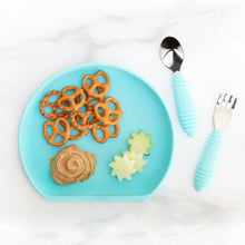 Load image into Gallery viewer, Bumkins Silicone Grip Plate: Blue holds pretzels, peanut butter, and cucumber slices on a marble background, with blue utensils nearby.
