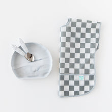 Load image into Gallery viewer, Toddler utensils rest inside Bumkins Silicone Grip Plate: Marble next to a folded gray &amp; white checkered bib on a white background.

