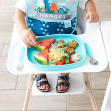 Load image into Gallery viewer, A toddler in a high chair enjoys a meal from a Bumkins Silicone Grip Tray: Blue, featuring watermelon, noodles, and star-shaped treats.
