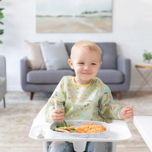 Load image into Gallery viewer, A toddler in a high chair enjoys food from a Bumkins Silicone Grip Tray: Marble. A gray couch and painting add charm to the cozy scene.
