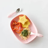 Bumkins Silicone Grip Tray: Pink holds pineapple, red pepper slices, and pesto spaghetti with pink utensils on a white background.