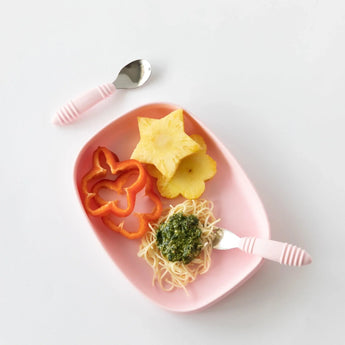 Bumkins Silicone Grip Tray: Pink holds pineapple, red pepper slices, and pesto spaghetti with pink utensils on a white background.