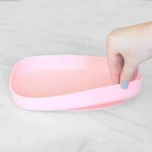 Load image into Gallery viewer, A hand holds a Bumkins Silicone Grip Tray: Pink, demonstrating the suction cup bottom on a marble surface.
