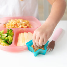 Load image into Gallery viewer, A child's hand reaches to dip an apple slice in peanut butter from a Bumkins Silicone Little Dipper Combo 2 Pack: Aqua Jelly at a white table.
