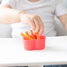 Load image into Gallery viewer, A child eagerly reaches for carrot sticks in a red Bumkins Silicone Little Dipper 3-Pack: Tutti-Frutti on a high chair tray.
