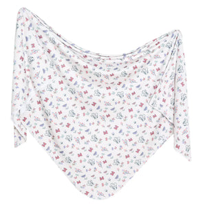 Copper Pearls Knit Swaddle Blanket, Minnie Mouses Bowquet is a white shawl with butterfly and flower patterns in a cozy triangular shape.